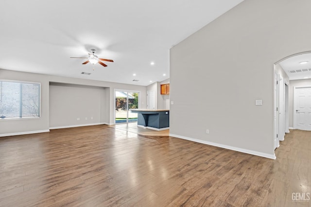 unfurnished living room with light wood-type flooring, vaulted ceiling, and ceiling fan