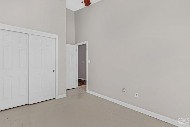 unfurnished bedroom featuring ceiling fan, a closet, and a high ceiling