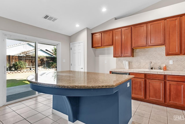 kitchen featuring a center island, light tile patterned flooring, lofted ceiling, and sink