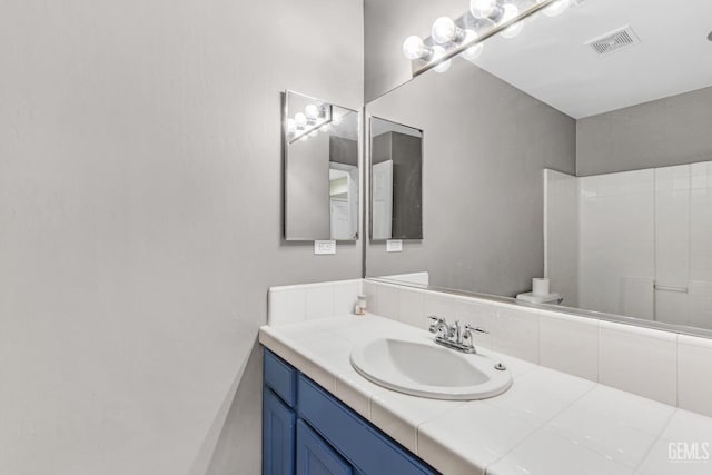 bathroom featuring a shower, vanity, and toilet