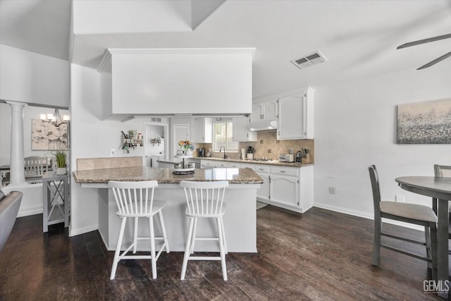 5812 Seasons Valley Ct, Bakersfield, CA 93313 - kitchen with a peninsula, white cabinets, dark wood-type flooring, a breakfast bar area, and a ceiling fan