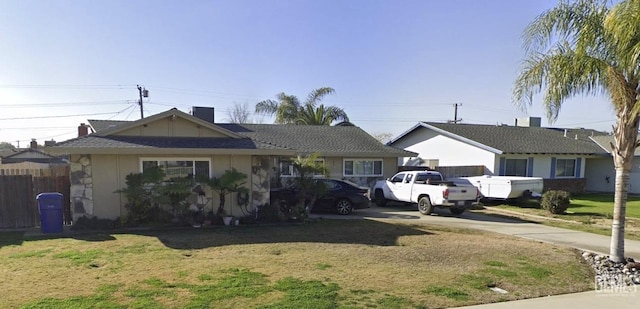 ranch-style home featuring fence, driveway, and a front lawn