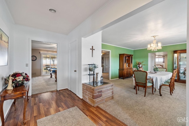 dining area with dark hardwood / wood-style flooring, ornamental molding, and a notable chandelier