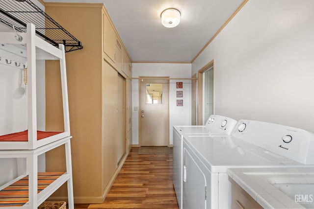 clothes washing area featuring washer and clothes dryer, light hardwood / wood-style floors, and ornamental molding