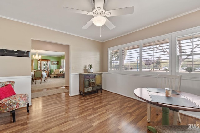 living area featuring hardwood / wood-style flooring, ceiling fan with notable chandelier, and ornamental molding