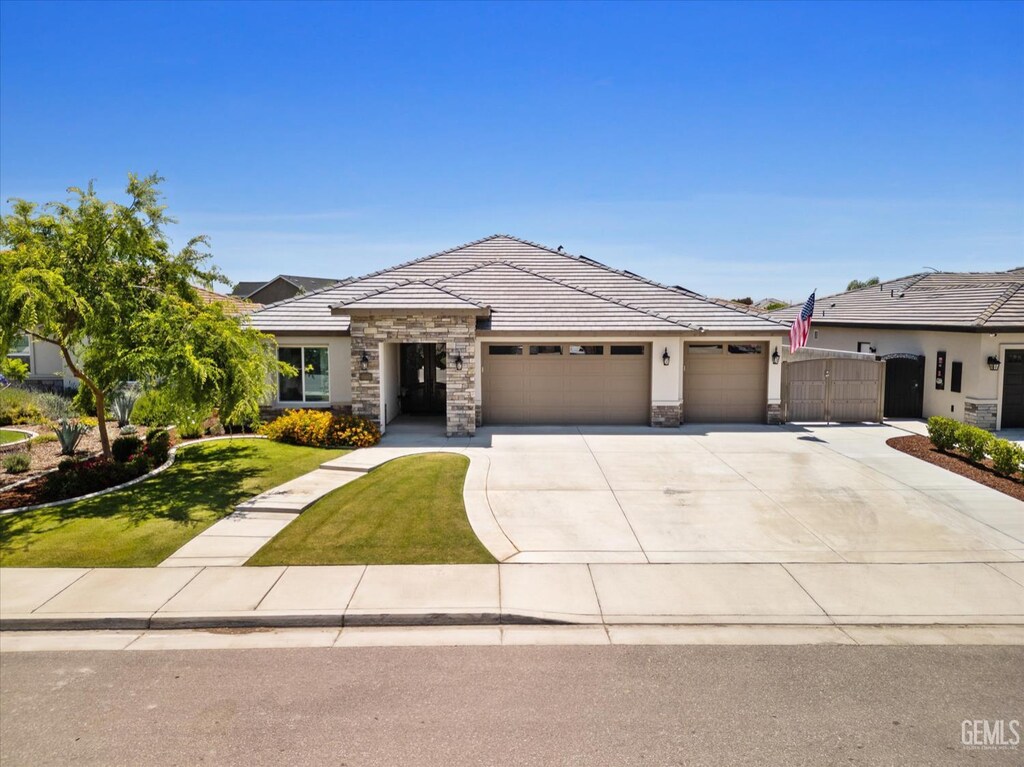 15017 Mistletoe Ave, Bakersfield, CA 93314 - view of front of home featuring an attached garage, stone siding, driveway, a front yard, and stucco siding
