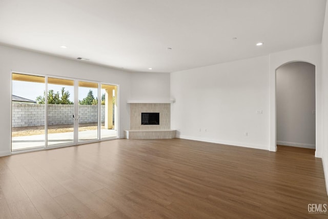 unfurnished living room featuring a tile fireplace and dark wood-type flooring