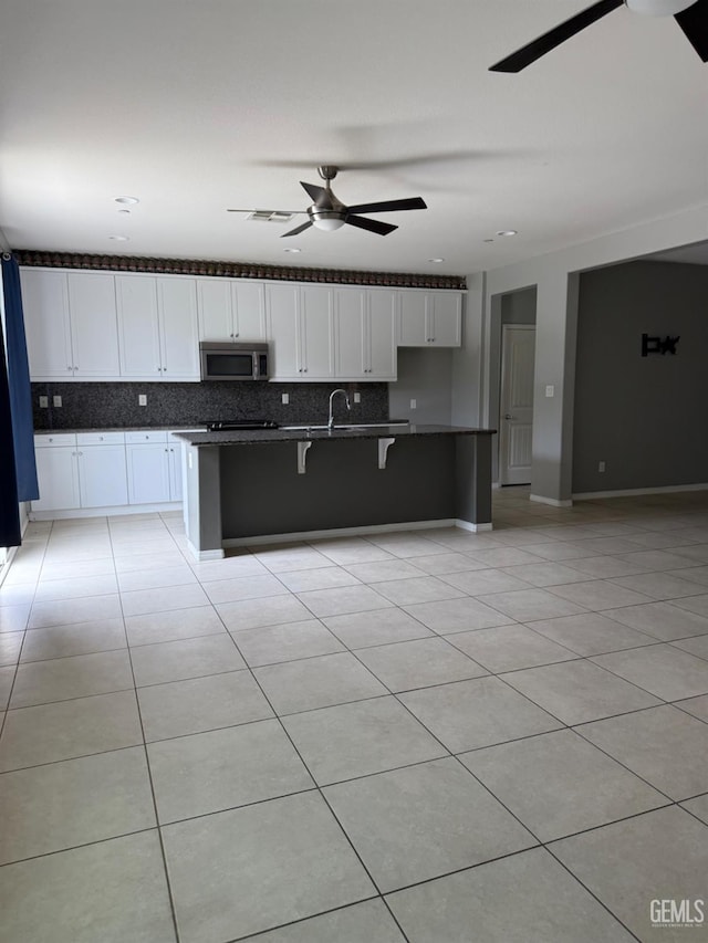 6511 Epley Ct, Bakersfield, CA 93313 - kitchen featuring stainless steel microwave, ceiling fan, light tile patterned floors, backsplash, and white cabinets