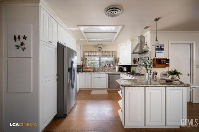 kitchen with wall chimney exhaust hood, appliances with stainless steel finishes, kitchen peninsula, and white cabinets