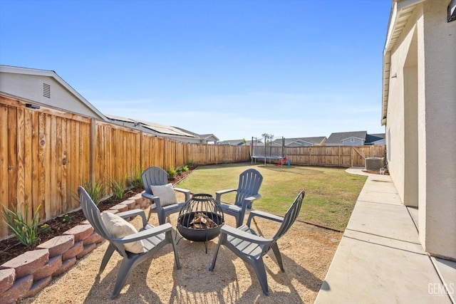 view of patio / terrace with central air condition unit, a fire pit, and a trampoline