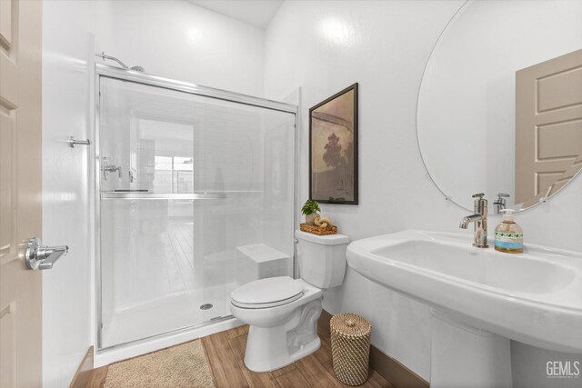 bathroom featuring hardwood / wood-style flooring, a shower with door, and toilet