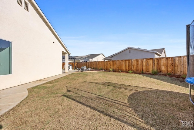 view of yard featuring a trampoline and a patio