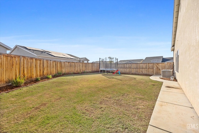 view of yard with a trampoline and central AC