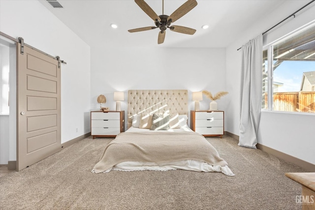 carpeted bedroom with a barn door and ceiling fan