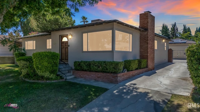 1825 Camino Primavera, Bakersfield, CA 93306 - ranch-style home with a chimney, stucco siding, and a lawn