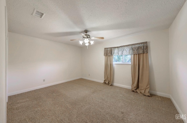 spare room featuring baseboards, visible vents, ceiling fan, a textured ceiling, and light carpet