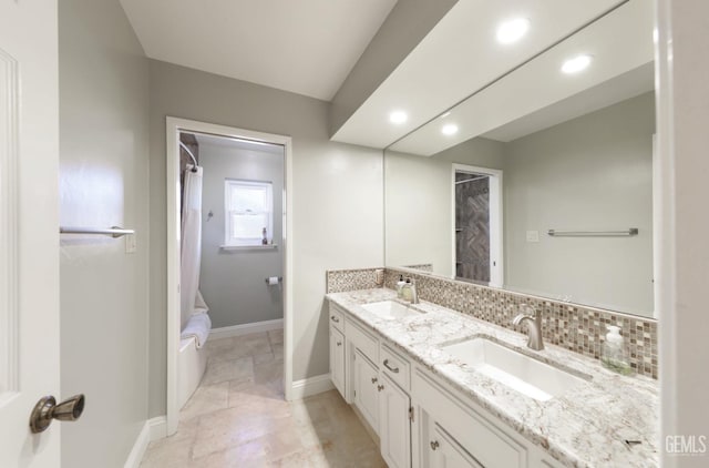 bathroom featuring double vanity, decorative backsplash, baseboards, and a sink