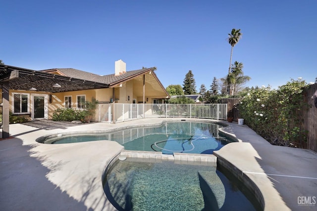 view of swimming pool featuring a patio, fence, and a pool with connected hot tub