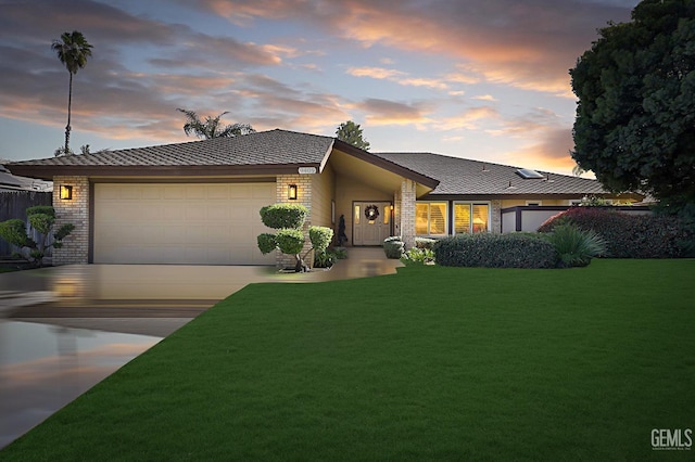 view of front of property with concrete driveway, brick siding, an attached garage, and a front lawn