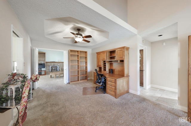 office space with light carpet, a fireplace, a textured ceiling, and baseboards