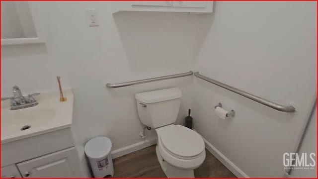 bathroom featuring baseboards, toilet, vanity, and wood finished floors