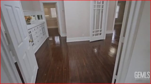 unfurnished bedroom with dark wood-type flooring and baseboards
