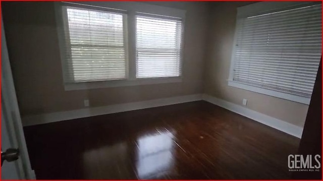 unfurnished room with dark wood-style floors and baseboards