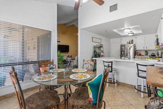 dining room featuring lofted ceiling, visible vents, ceiling fan, and light tile patterned flooring