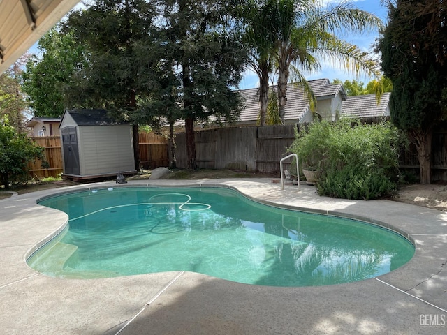 view of swimming pool with an outdoor structure, a storage unit, a fenced backyard, and a fenced in pool