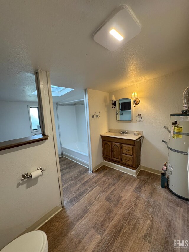 1 Jasper Ave, Rosamond, CA 93561 - full bathroom featuring strapped water heater, a skylight, vanity, a textured ceiling, and wood finished floors