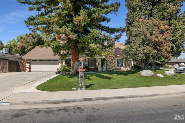 view of property hidden behind natural elements with a garage, a front yard, and central AC unit