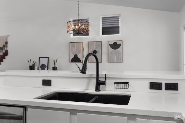 interior details featuring pendant lighting, a sink, and light stone countertops