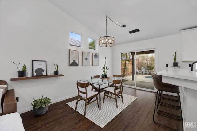 dining area featuring lofted ceiling, dark wood-style flooring, a notable chandelier, and baseboards