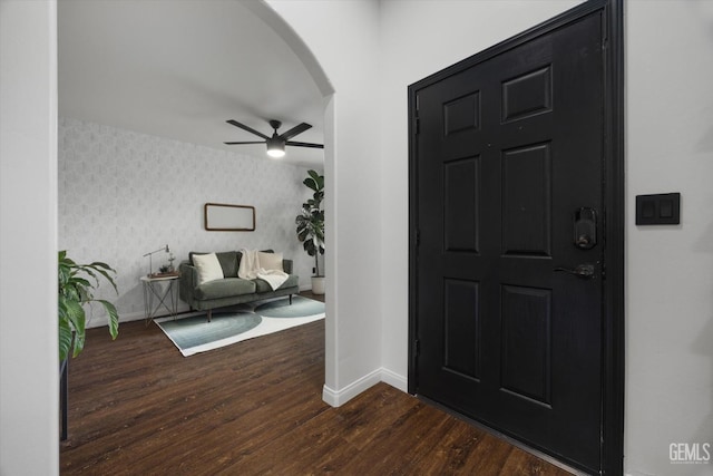 entrance foyer featuring arched walkways, baseboards, a ceiling fan, and wallpapered walls