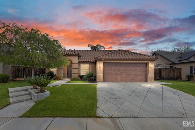 mediterranean / spanish home featuring an attached garage, driveway, a front lawn, and stucco siding