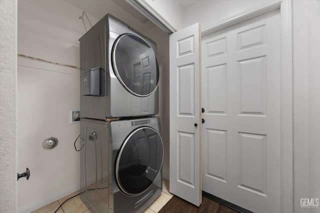 laundry area featuring stacked washer / drying machine, laundry area, tile patterned flooring, and baseboards