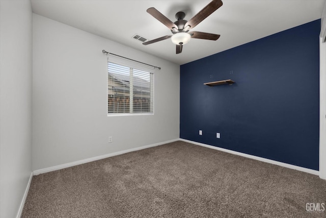 carpeted spare room with baseboards, visible vents, and ceiling fan