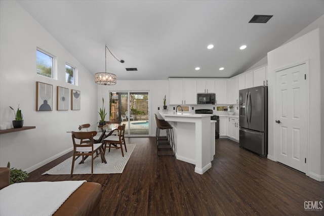 kitchen with light countertops, visible vents, vaulted ceiling, black microwave, and stainless steel fridge with ice dispenser