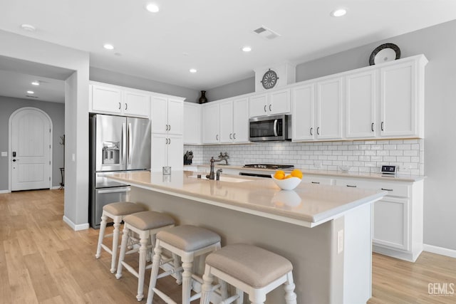 kitchen featuring a breakfast bar, light countertops, appliances with stainless steel finishes, white cabinetry, and a sink