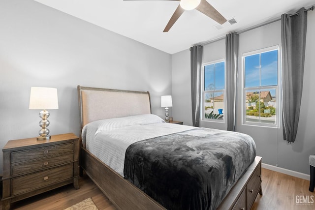 bedroom with light wood-type flooring, visible vents, ceiling fan, and baseboards