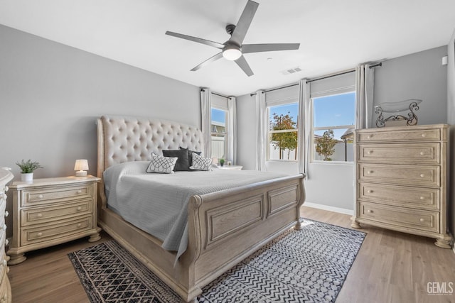 bedroom with light wood-style flooring, visible vents, ceiling fan, and baseboards