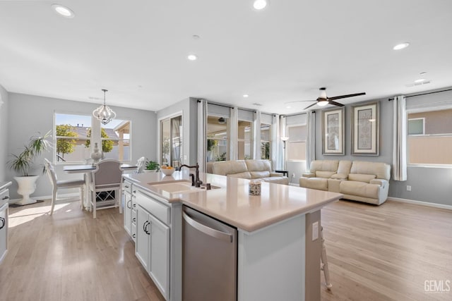 kitchen with a sink, open floor plan, light countertops, dishwasher, and an island with sink