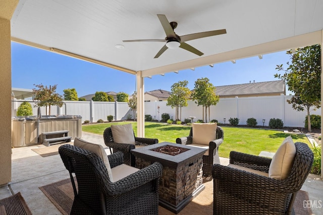 view of patio with a ceiling fan, an outdoor fire pit, a fenced backyard, and a hot tub