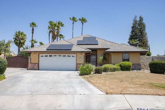 9004 Cresson Ct, Bakersfield, CA 93307 - view of front facade with concrete driveway, an attached garage, a gate, roof mounted solar panels, and stucco siding