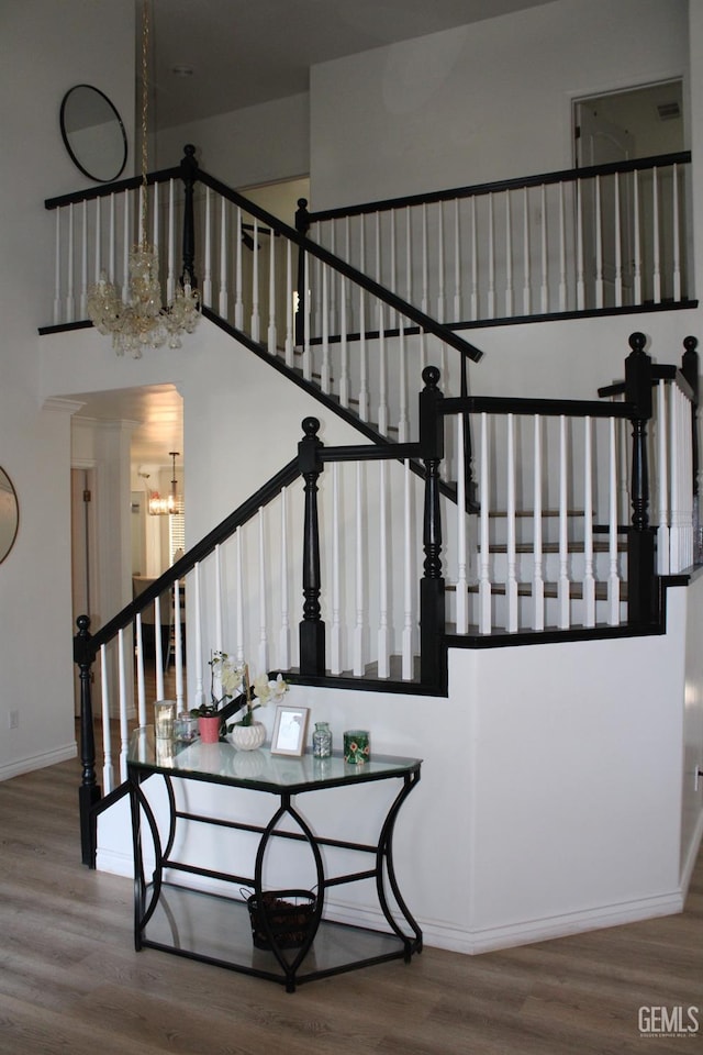 stairway with hardwood / wood-style flooring, a high ceiling, and a notable chandelier