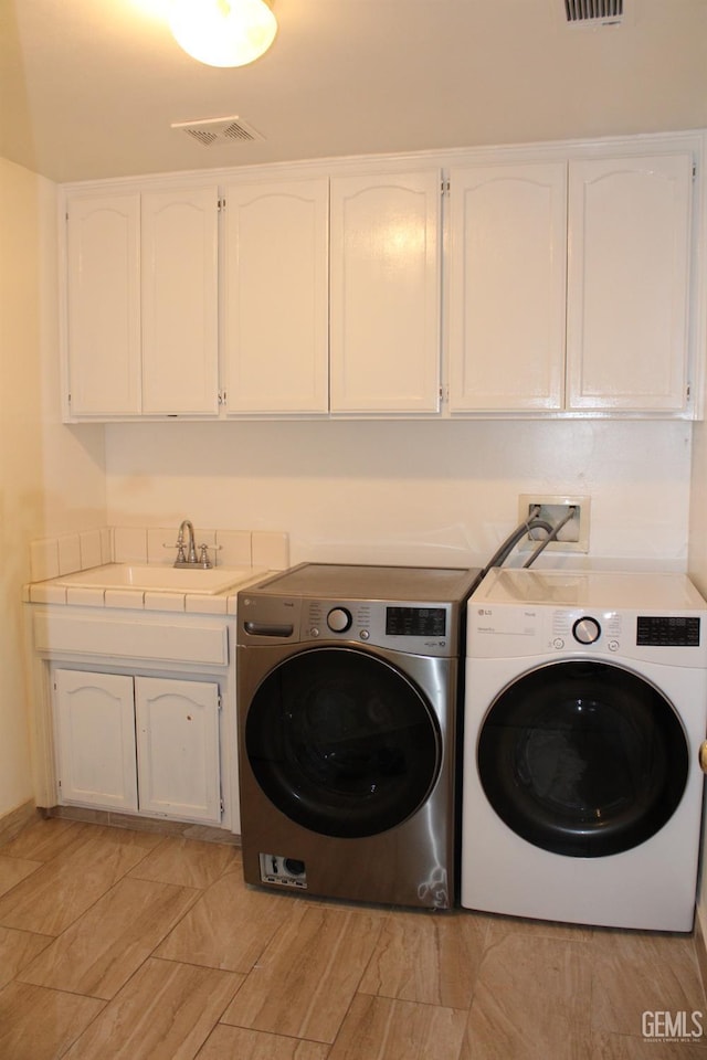 washroom with cabinets and washing machine and dryer