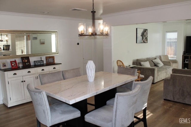 dining space featuring dark hardwood / wood-style flooring, crown molding, and a chandelier