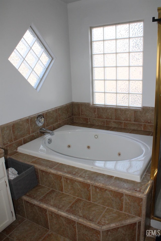 bathroom featuring tile patterned flooring, vanity, and a relaxing tiled tub