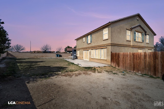 property exterior at dusk with a patio area