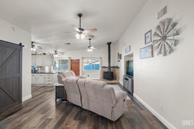 404 Mckinley St, Taft, CA 93268 - living room with a wood stove, a barn door, dark wood-style flooring, and a ceiling fan
